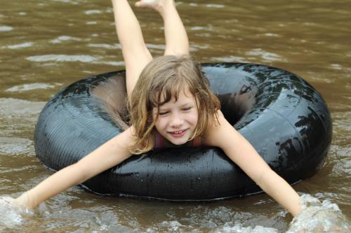 a young girl laying in an inner tube in the water at Lions Rock Rapids - Lodge in Hazyview