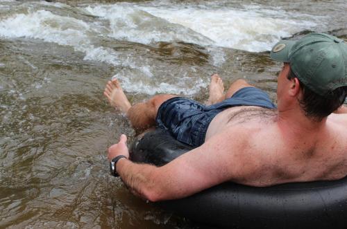 a man laying on a raft in the water at Lions Rock Rapids - Lodge in Hazyview