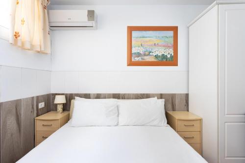 Un dormitorio con una cama blanca y una pintura en la pared en Villa Palm Mar, en Palm-mar