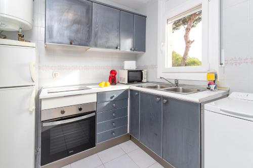 a kitchen with gray cabinets and a sink and a window at Apartaments Aiguablava in Begur