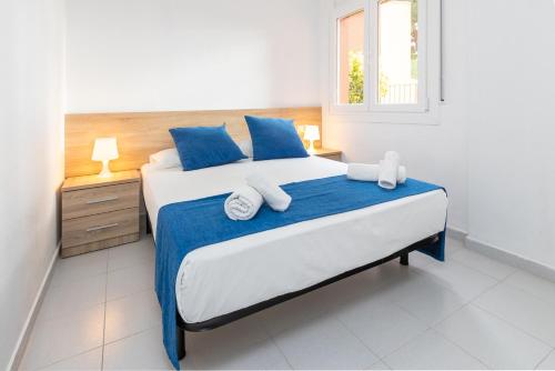 a bedroom with a bed with blue and white sheets and a window at Apartaments Aiguablava in Begur