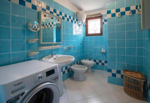 ein blau gefliestes Badezimmer mit einer Waschmaschine darin in der Unterkunft Villa Adelaide in Villasimius