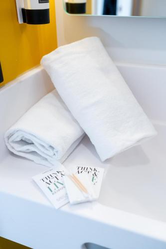 a pile of towels sitting on a counter in a bathroom at B&B HOTEL Massy Gare TGV in Massy