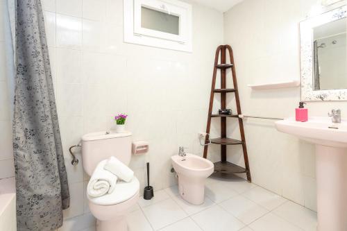 a white bathroom with a toilet and a sink at Apartaments Aiguablava in Begur
