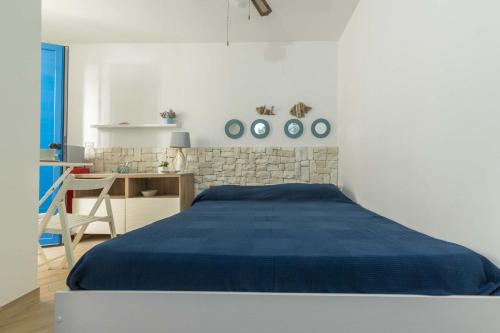 a white bedroom with a blue bed and a desk at L`Ebrezza by BarbarHouse in Campomarino