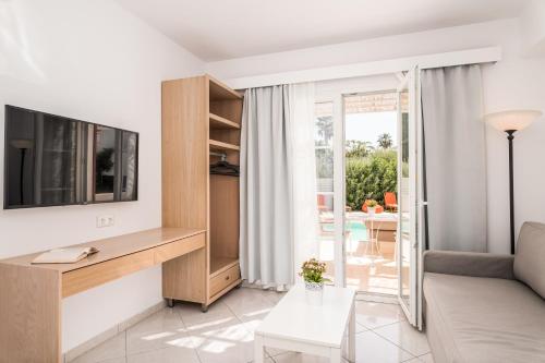 een woonkamer met een tv en een bank bij Hydrele Beach Hotel & Village in Potokáki