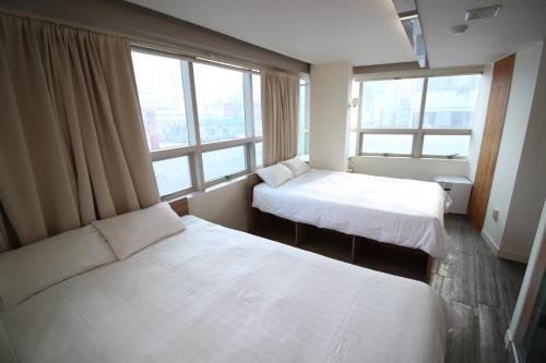 two beds in a room with two windows at Hostel Kpop in Seoul