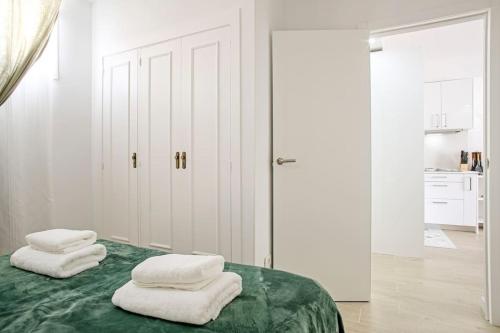 1 dormitorio con paredes blancas y 1 cama verde con 2 toallas blancas en Royal Suite Diamantes I With heated pool en Los Cristianos