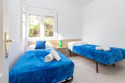 a bedroom with two beds with blue sheets and a window at Apartaments Aiguablava in Begur