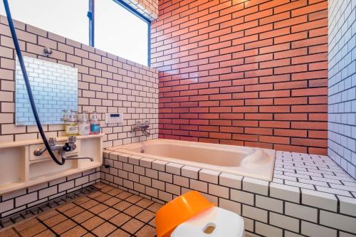 a bathroom with a tub and a red brick wall at Engawa House Momiji-With hot spring in Fujikawaguchiko
