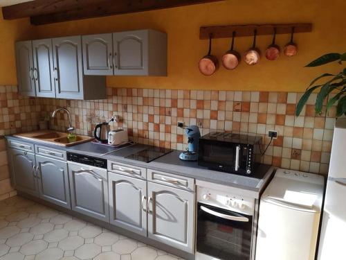 a kitchen with white cabinets and a sink and a microwave at Les Souchottes, charmante maisonnette in Bulligny