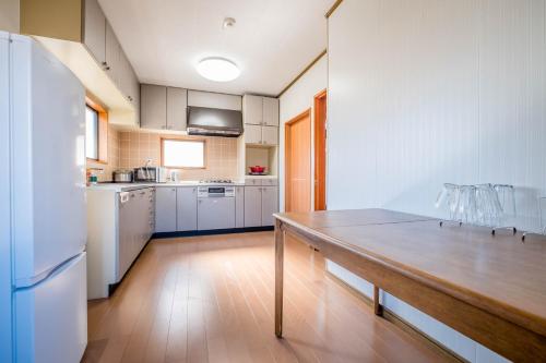 a kitchen with a wooden table and a refrigerator at Engawa House Momiji-With hot spring in Fujikawaguchiko