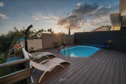 una terraza con piscina y 2 sillas junto a en HAUT DE VILLA avec piscine chez JP, en Petite Île