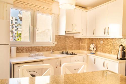 a kitchen with white cabinets and a sink and a window at Vibran in İzmir