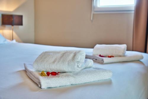 two towels sitting on top of a bed at Adonis Hotel Bayonne in Lahonce
