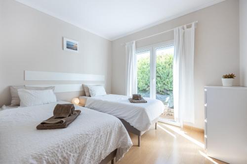 2 camas en una habitación blanca con ventana en Your Villa Algarve Private pool 5 min walk to beach, en Burgau