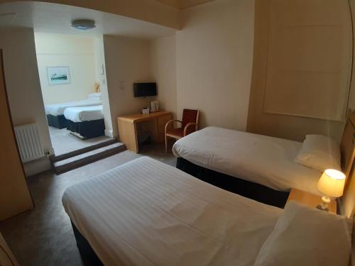 リバプールにあるハノーバー ホテル ＆ マッカートニーズ バーのベッド2台とデスクが備わるホテルルームです。