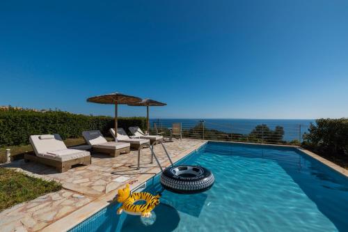 a swimming pool with two chairs and an umbrella at Astra Villas in Skala Kefalonias