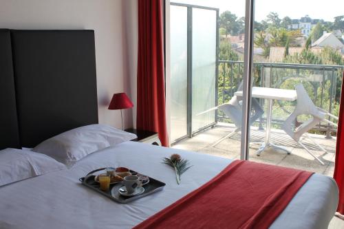 une chambre d'hôtel avec un plateau de nourriture sur un lit dans l'établissement Adonis La Baule, à La Baule