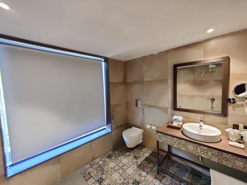 a bathroom with a white sink and a large window at Bhanu The Fern Forest Resort & Spa, Jambughoda in Jambughoda