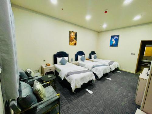 a hotel room with three beds and a couch at Daraysh Hotel in Sharjah