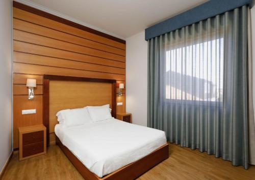 a bedroom with a bed and a large window at Montebelo Palácio dos Melos Viseu Historic Hotel in Viseu