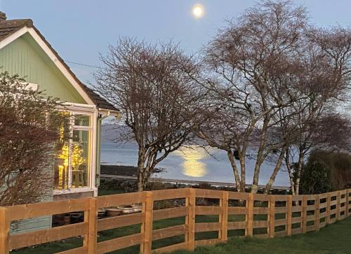 une clôture devant une maison avec la lune dans le ciel dans l'établissement Bay View, à Lochgilphead