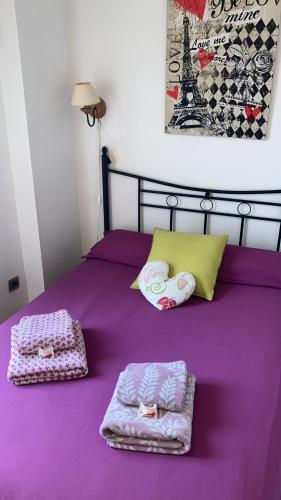een paars bed met twee handdoeken erop bij Carol's home in Zaragoza