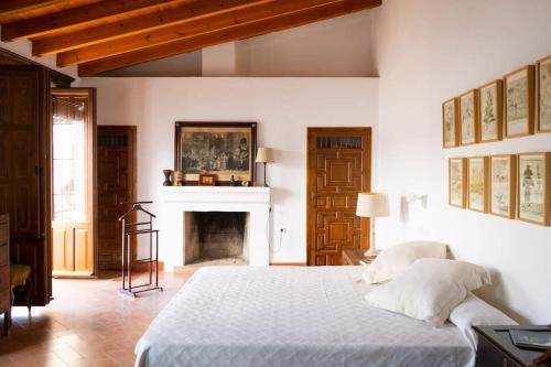 a bedroom with a white bed and a fireplace at Cortijo El Solano in Antequera