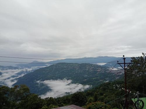 uma vista para um vale com nuvens e montanhas em Kalimpong View Stay em Kalimpong