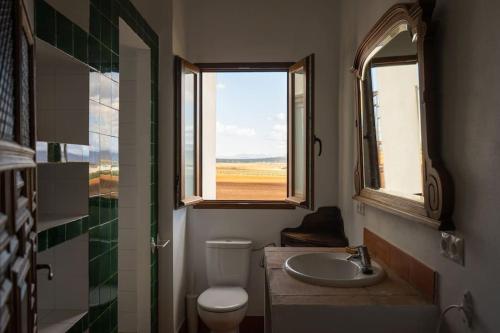 un bagno con servizi igienici e lavandino e 2 finestre di Cortijo El Solano ad Antequera