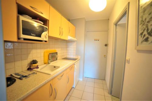 eine kleine Küche mit einer Spüle und einer Mikrowelle in der Unterkunft STUDIO SAINT CLAIR Vue Laterale MER in La Grande-Motte