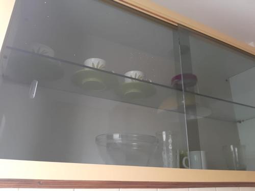 una estantería de cristal en una cocina con tazas. en Depto. 1 ambiente Plaza Mitre en Mar del Plata