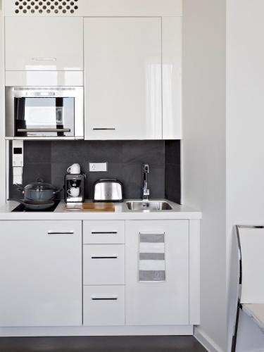 a white kitchen with a sink and a microwave at VISIONAPARTMENTS Berlin - contactless check-in in Berlin
