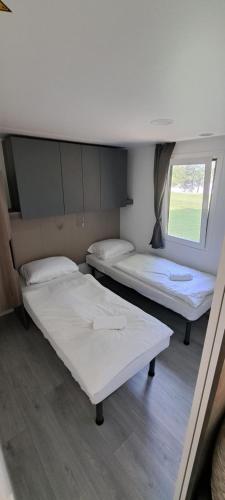 two beds in a room with a window at Camp Velenje in Velenje