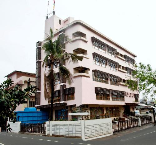 a pink building with a palm tree in front of it at Hotel Rains Inn in Guwahati