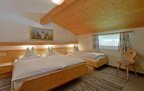 een slaapkamer met 2 bedden en een stoel. bij Ferienhaus Barbara in Ramsau im Zillertal