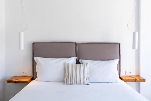 a bed with white sheets and pillows at Meliti Hotel (Adults Only) in Agios Nikolaos