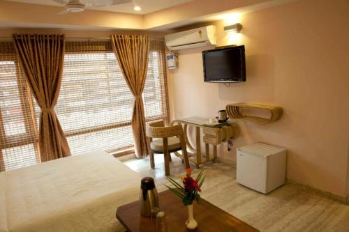 a hotel room with a bed and a desk and a television at Hotel Rains Inn in Guwahati