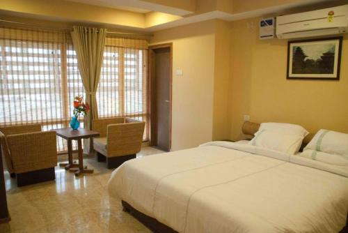a bedroom with a large white bed and a table at Hotel Rains Inn in Guwahati
