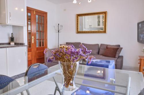 a vase of purple flowers sitting on a glass table at Apartamento en el centro de Portosin in Goyanes