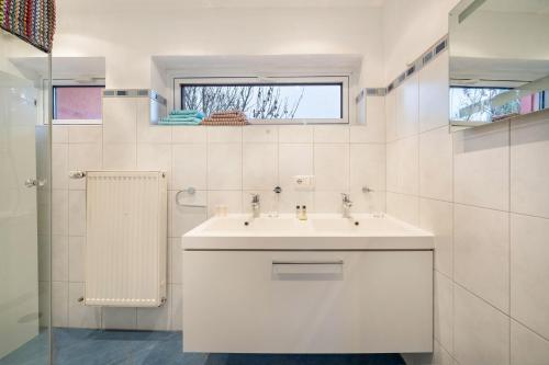 a white bathroom with a sink and a window at Haus Rose Muc City in Munich