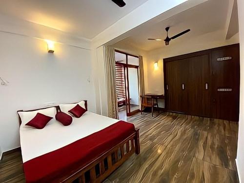 um quarto com uma cama grande e almofadas vermelhas em Coral Cove Beach Resort em Varkala