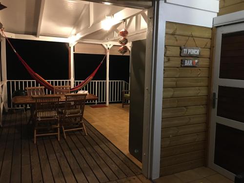 a room with a table and chairs on a deck at Grand bungalow avec piscine et vue mer in Bouillante