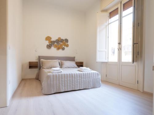 a white bedroom with a bed and a large window at MY HOUSE URBAN LUXURY B&B in Reggio Calabria