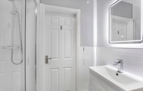 a white bathroom with a shower and a sink at York Suite on the historic Shambles, sleeps 6 in York