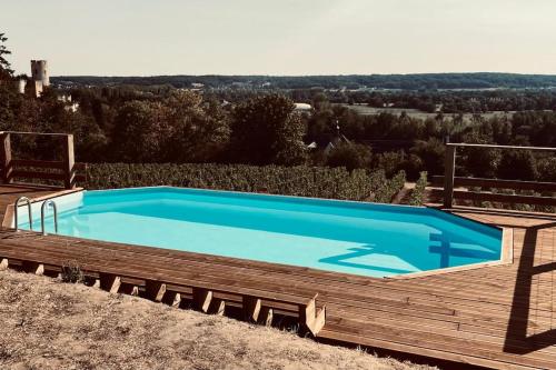 une grande piscine bleue sur une terrasse en bois dans l'établissement Maison vue panoramique depuis le coteau de Chinon, à Chinon