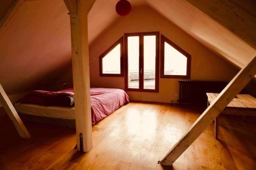 Cette chambre mansardée comprend un lit et une fenêtre. dans l'établissement Maison vue panoramique depuis le coteau de Chinon, à Chinon