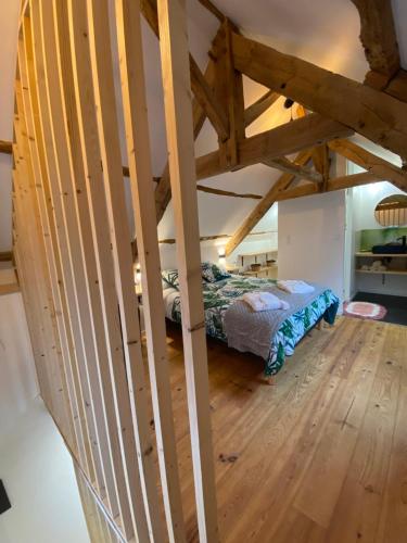 a attic room with a bed and a wooden floor at A La Mémoire de Merlin " Gîte Le Miroir Aux Fées " in Saint-Malon-sur-Mel