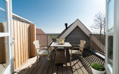 una terraza de madera con mesa y sillas. en Appartement N05 Bakboord & Stuurboord, en Oost-Vlieland